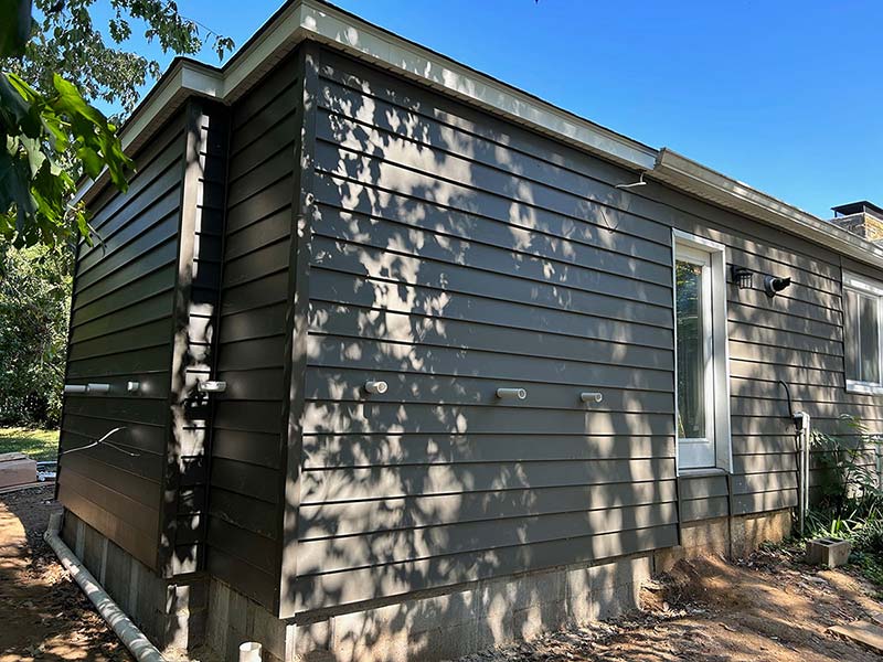 Corner of a newly installed vinyl siding project in gray
