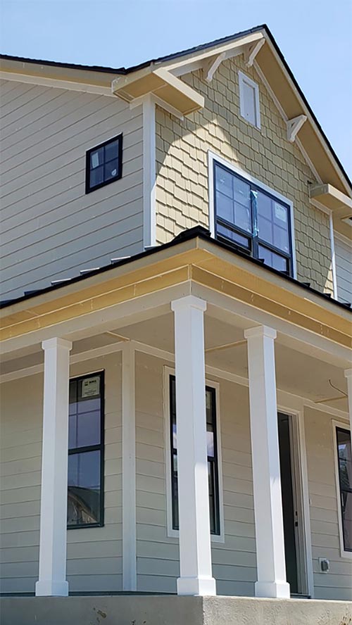 Siding Installation on a two story house with white columns on the front porch