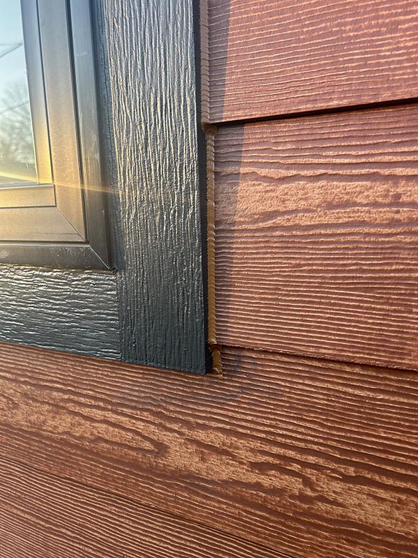 Close Up of profession siding installation and window caulking