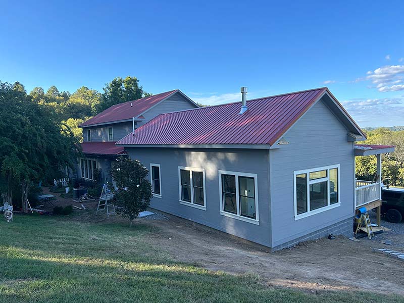 Image of new siding installation on log home with red roof